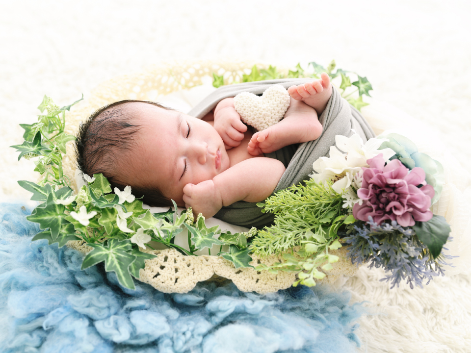 花飾りのゆりかごの中で眠っている赤ちゃんの写真